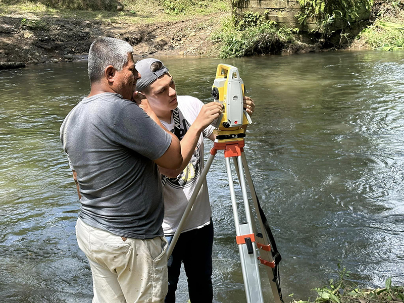 A WSU engineering student works with a Ecuadorian village to take measurements for a bridge. 