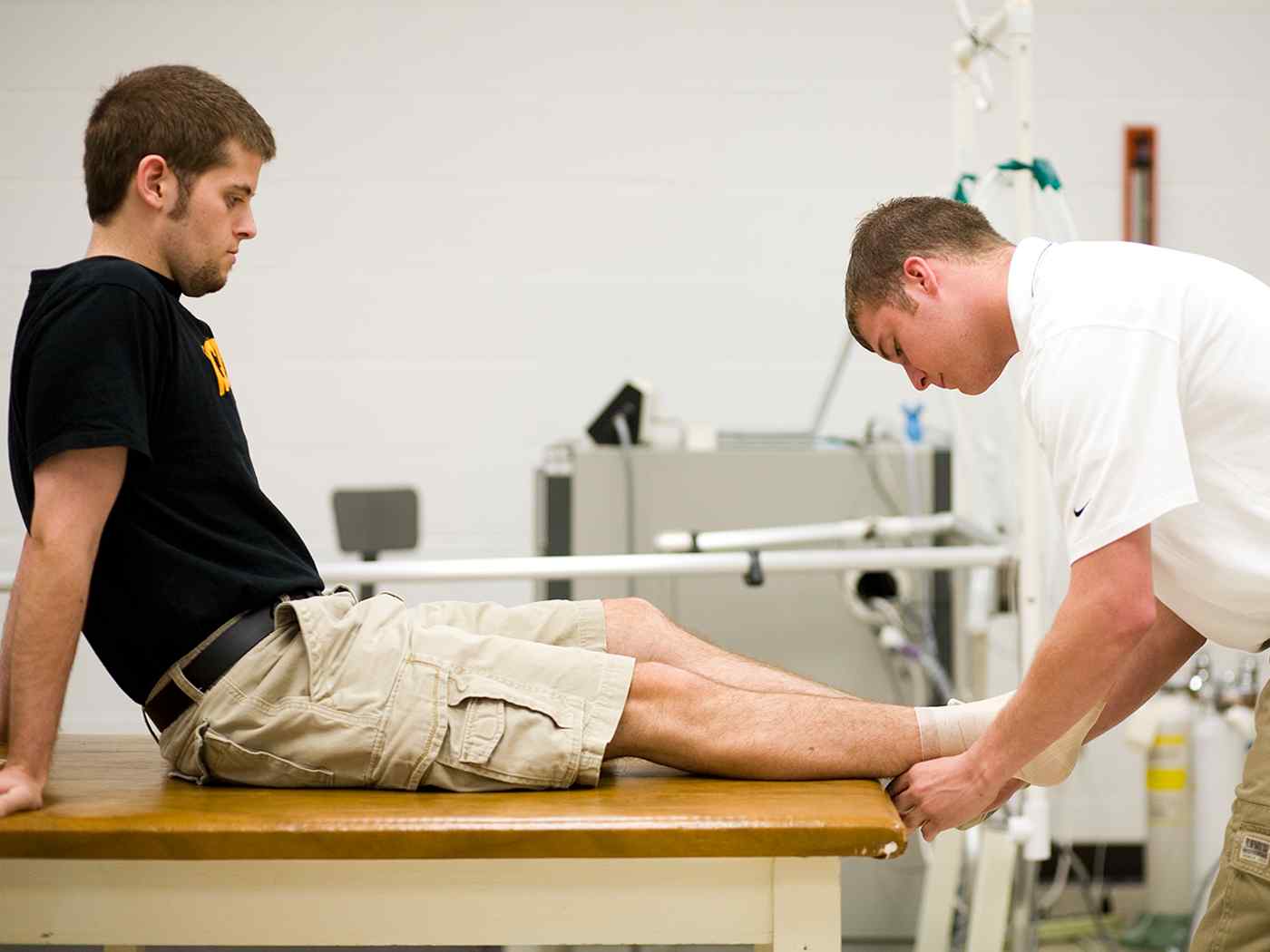 An athletic training student wraps another student's foot